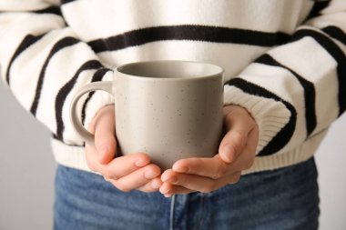 Gri arka planda seramik bardağı olan kadın, yakın plan.