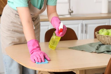 Mutfakta yemek masasını temizleyen genç kadın, yakın plan.