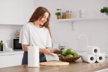 Mutfakta salatalık silen kağıt peçeteli genç bir kadın.