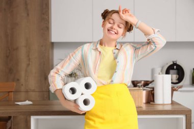 Mutfakta kağıt peçeteleri olan yorgun genç bir kadın.