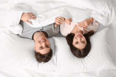 Genç çift yatakta yan yana yatıyor.