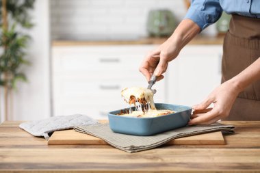 Spatulası olan kadın mutfaktaki fırından lezzetli bir lazanya alıyor.