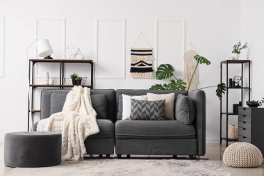 Oturma odasının içinde siyah kanepe, puf ve raf üniteleri var. Yin Yang konsepti