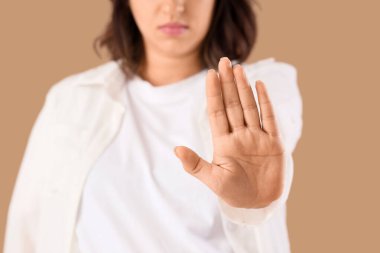 Bej arka planda DUR hareketi gösteren genç bir kadın, yakın plan. Kural kavramı