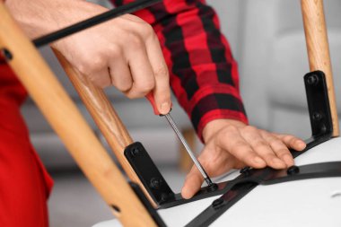 Erkek marangoz vidayı tornavidayla sıkıyor, yakın plan.