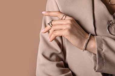 Gri yüzüklü, bilezik ve kolyeli şık ceketli güzel bir bayan.