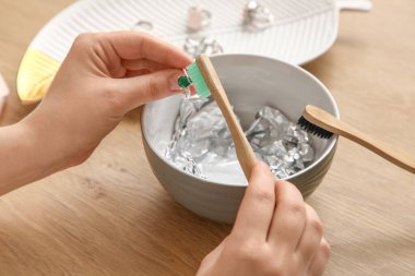 Masanın yanındaki gümüş halkayı temizleyen genç kadın, yakın plan.