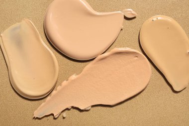 Kahverengi arka planda sıvı makyaj temeli örnekleri