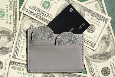 Yeşil arka planda bitcoin, kredi kartı ve dolar banknotları olan cüzdan
