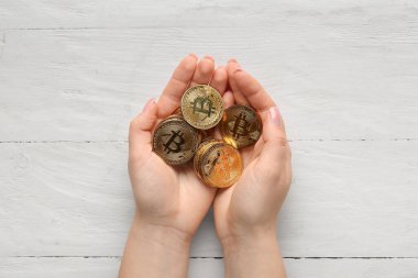 Beyaz ahşap arka planda altın sikkeleri olan kadın eller.