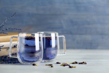 Mavi ahşap arka planda bir fincan kelebek bezelyesi çayı.