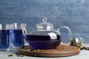 Çaydanlık ve bir bardak kelebek arkaplanda bezelye çiçeği çayı.