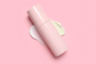 Pembe arka planda numune içeren bir şişe kozmetik ürünü.