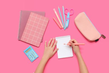 Pembe arka planda sabit duran çocuk elleri ve keçeli kalem. Üst görünüm