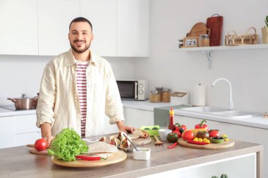 Genç adam mutfakta lezzetli Meksika tacoları hazırlıyor.