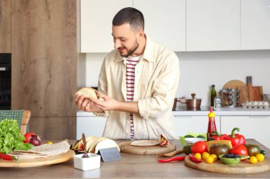 Genç adam mutfakta lezzetli Meksika tacoları hazırlıyor.