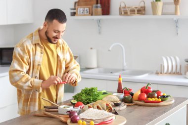 Genç adam mutfakta lezzetli Meksika tacoları hazırlıyor.