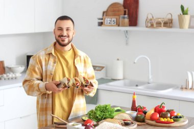 Genç adam mutfakta lezzetli Meksika tacoları hazırlıyor.