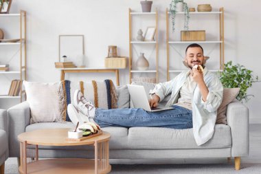 Bilgisayarlı genç adam evde lezzetli tacolar yiyor.