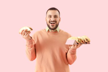 Pembe arka planda lezzetli tacoları olan genç bir adam.