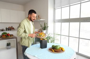 Mutfakta yemek pişirirken gübre kutusu ve sebze artıklarıyla gezen genç adam.