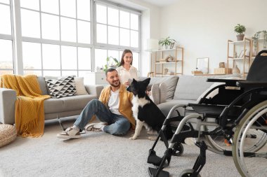 Evde köpeği ve tekerlekli sandalyesi olan genç bir çift