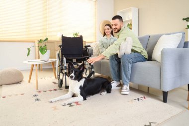 Kocası, tekerlekli sandalyesi ve köpeği olan genç bir kadın.