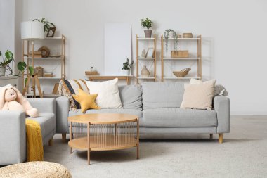 Masalı gri koltuklar, raf üniteleri ve ışık duvarının yanındaki boş poster.