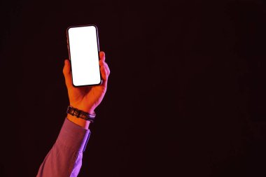 Karanlık arka planda boş cep telefonu tutan adam