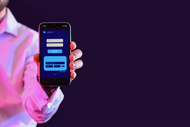 Karanlık arka planda bankacılık uygulaması olan cep telefonu tutan adam, yakın plan.