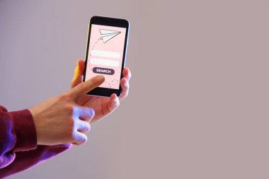 Cep telefonlu bir adam gri arka planda online bilet ayırtıyor.