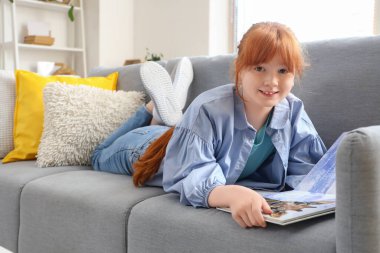 Evde kitap okuyan kızıl saçlı tatlı bir kız.