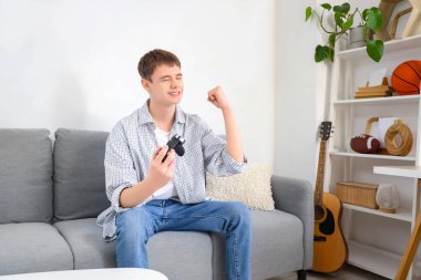 Evdeki kanepede video oyunu oynayan mutlu genç çocuk.