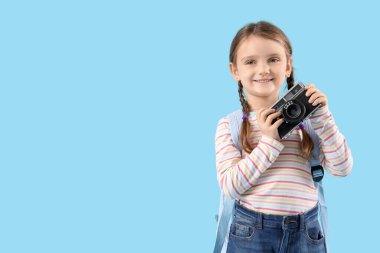 Mavi arka planda fotoğraf makinesi olan tatlı bir kız.