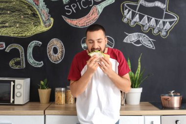 Genç adam evde lezzetli taco yiyor.