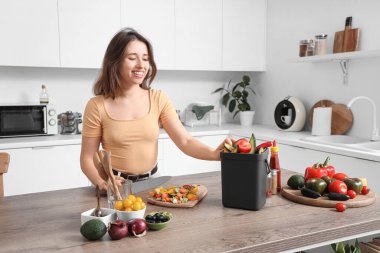 Mutfakta yemek pişirirken gübre kutusu olan genç bir kadın.