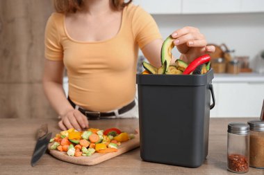 Mutfakta yemek pişirirken gübre kutusu olan genç bir kadın.