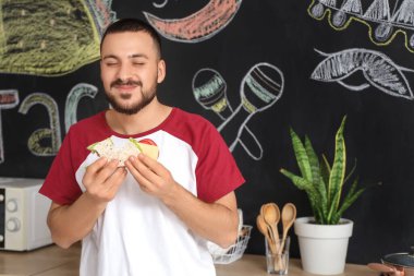 Genç adam evde lezzetli taco yiyor.