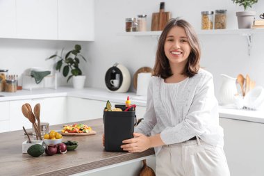 Mutfakta gübre kutusu olan genç bir kadın.