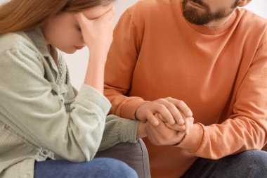 Evdeki kanepede üzgün karısından özür dileyen genç adam, yakın plan.