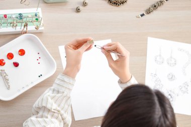 Kadın mücevher tasarımcısı atölyede yüzük yapıyor.