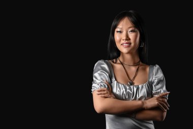 Siyah arka planda gümüş bluzlu güzel bir Asyalı kadın.