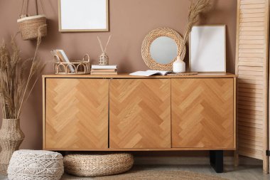 Oturma odasının içinde, bej duvarın yanında katlanan perde ve çekmeceler var.