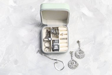 Gri arka planda güzel gümüş mücevherleri ve kol saati olan bir organizatör.