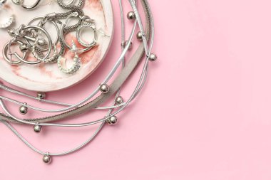 Pembe arka planda güzel gümüş mücevherleri olan tepsi