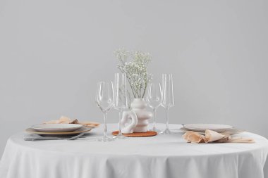 Açık arkaplanda vazoda çiçeklerle servis edilen restoran masası