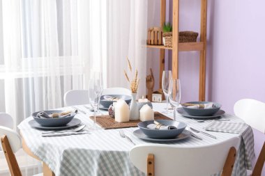 Yemek odasında mum, buğday ve gri peçeteli şık bir masa. Yakın çekim.