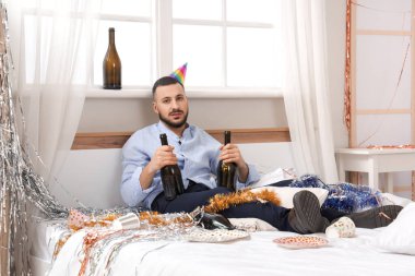 Şişeli genç adam yatak odasındaki partiden sonra kendini kötü hissediyor.