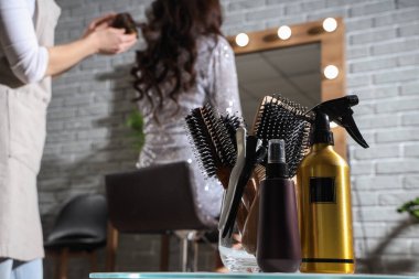 Güzellik salonunda müşteriyle çalışan kuaföre karşı masanda stil araçları, yakın plan.