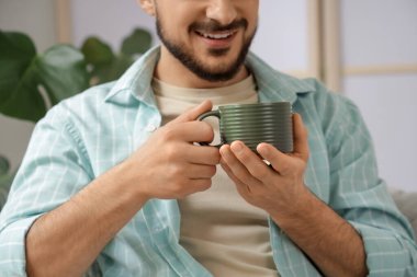 Evde yeşil seramik bardaklı genç adam, yakın plan.